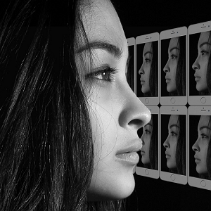Mentaltraining Selbsterfahrung: seitliches Profilbild einer jungen Frau in schwarzweiß, das Bild wird in mehreren Mobiltelefonen gespiegelt